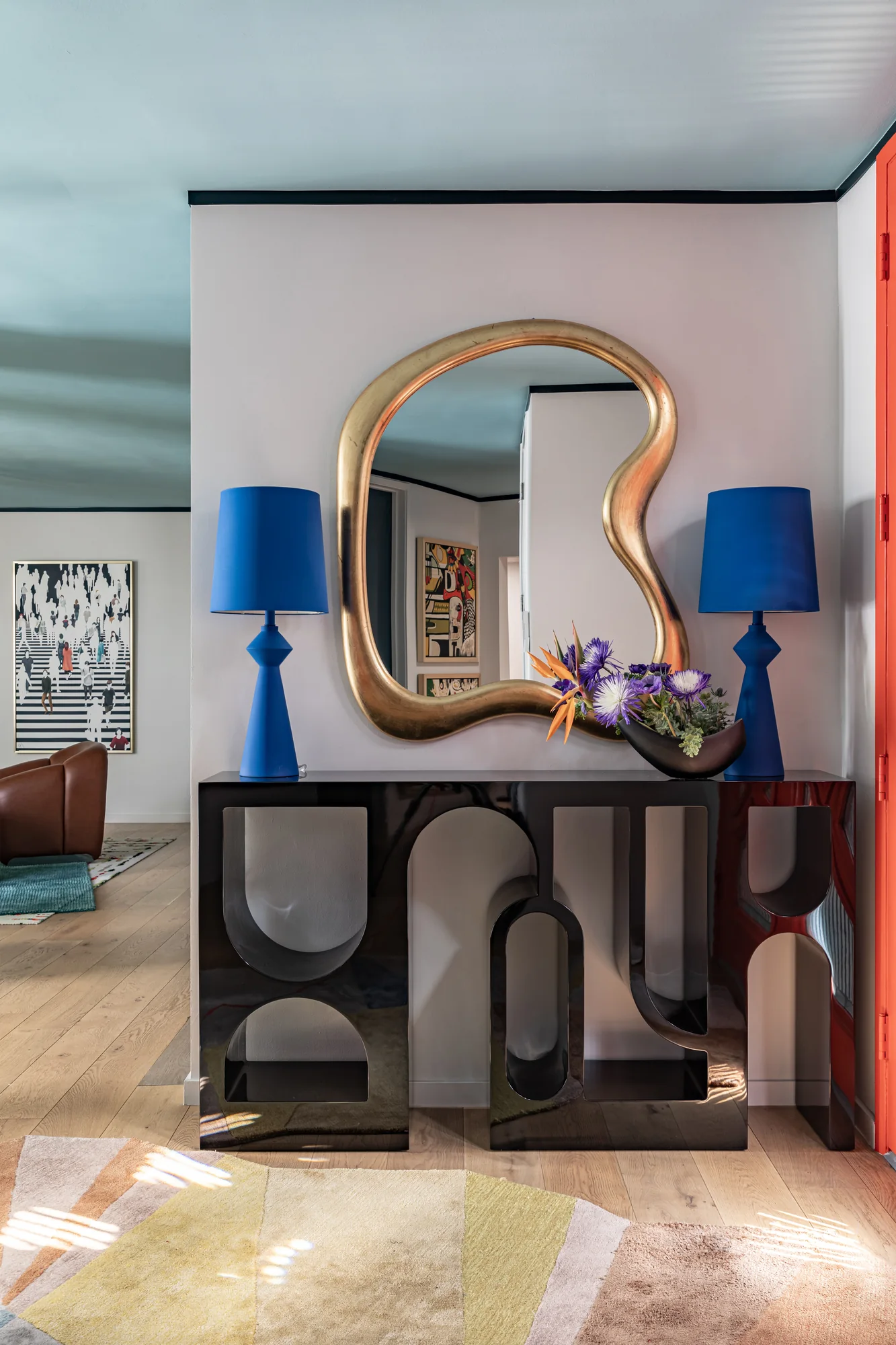 Entry console with a gold biomorphic mirror and cobalt lamps
