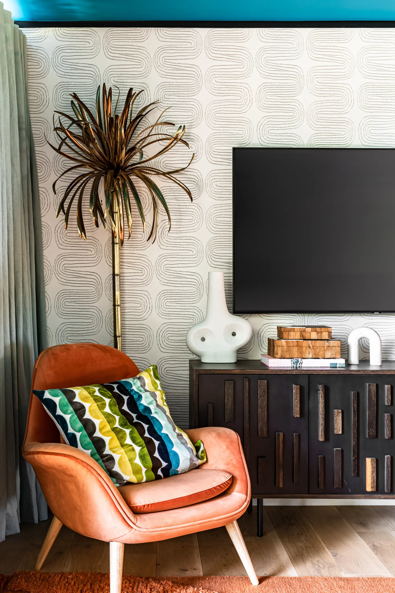 Bedroom corner with an orange lounge chair and a dried palm
