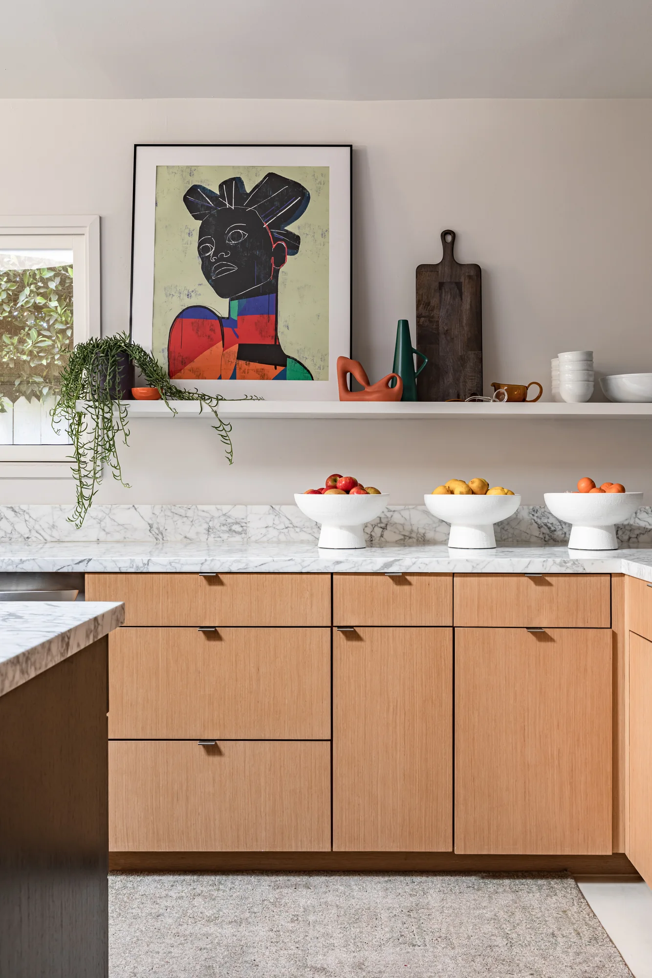 Kitchen shelf styled with art, ceramics and fruit stands
