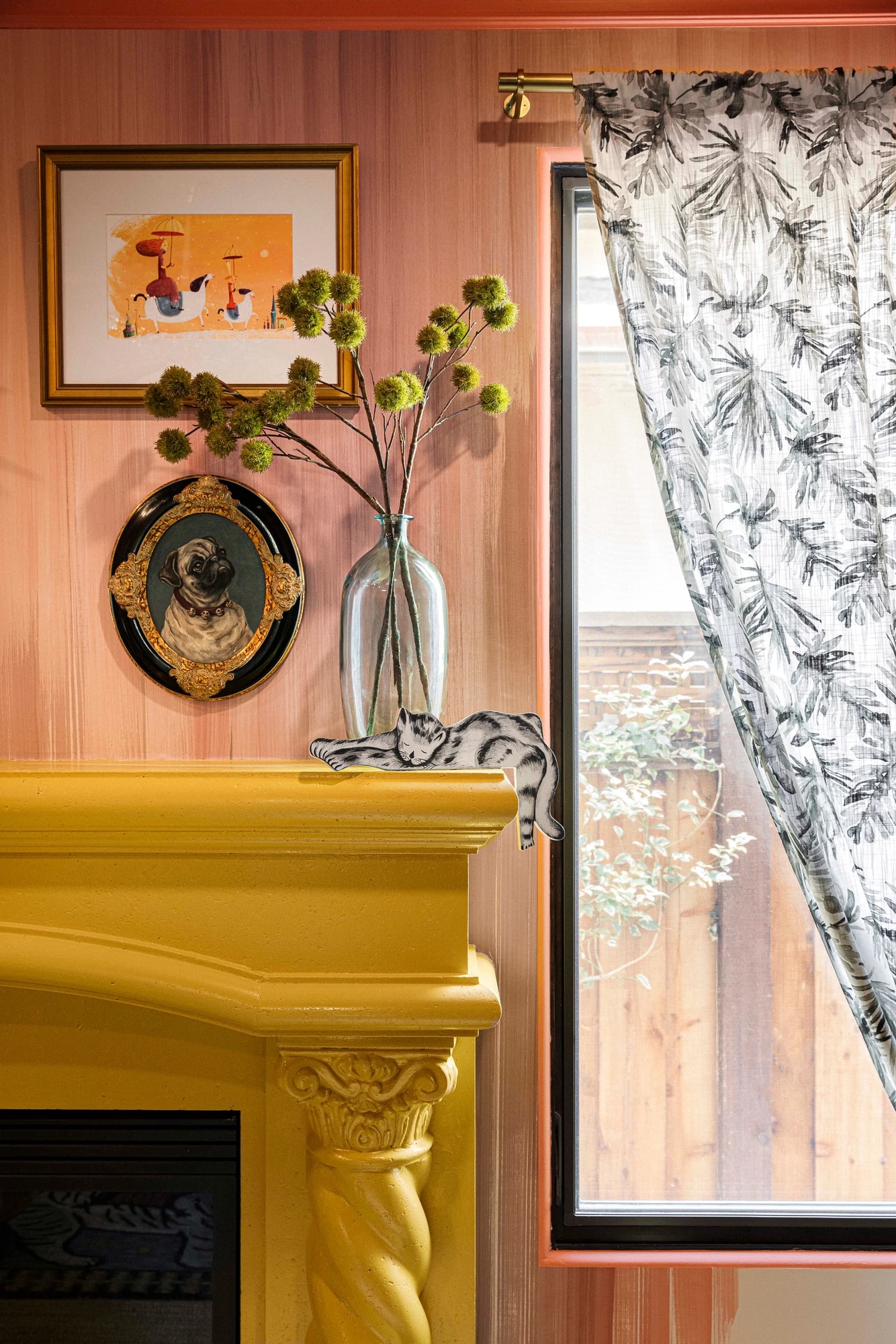The yellow mantel beside a window hung with a botanical-print curtain