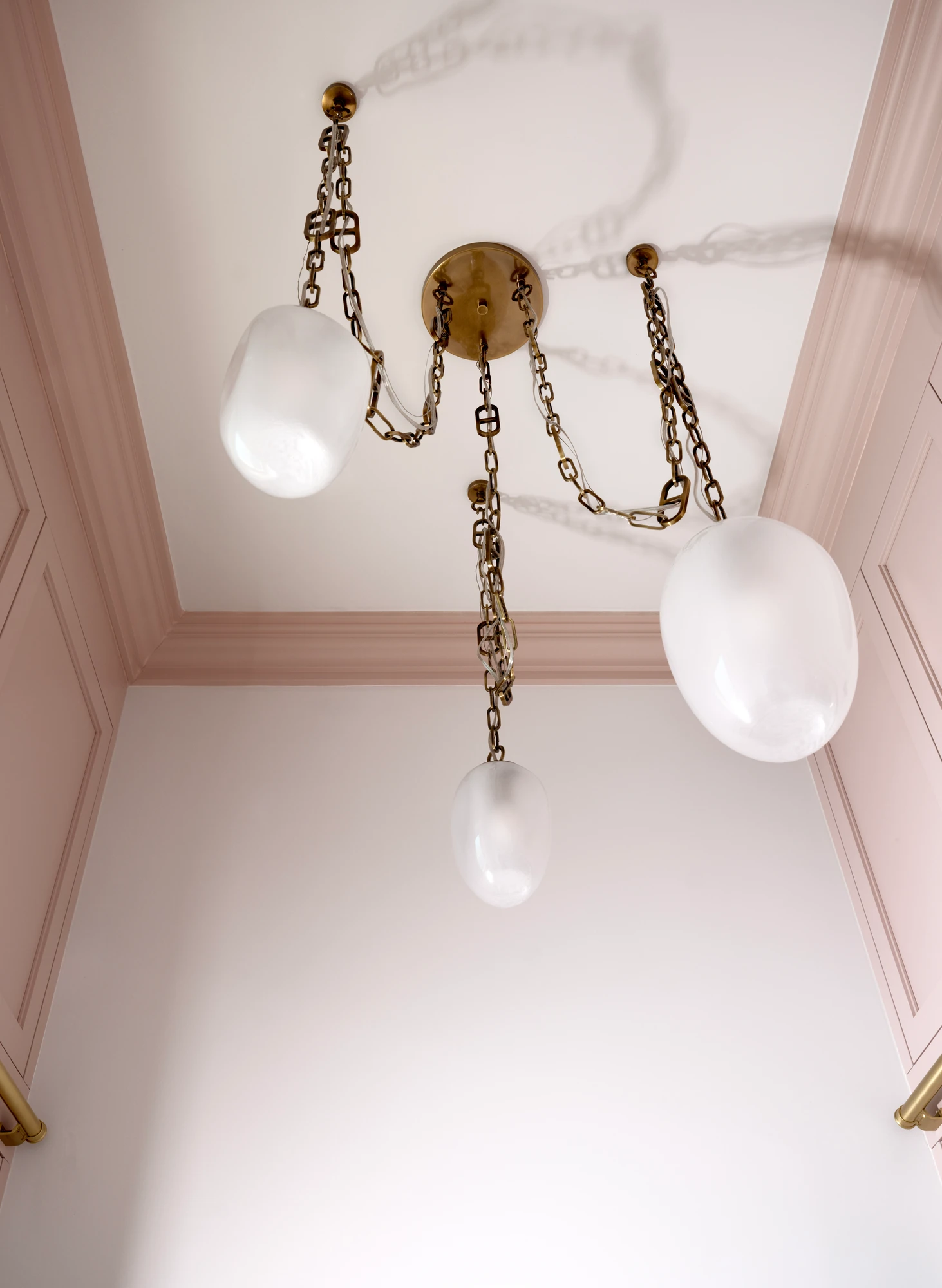 Blush stairwell ceiling with chain-hung glass pendants