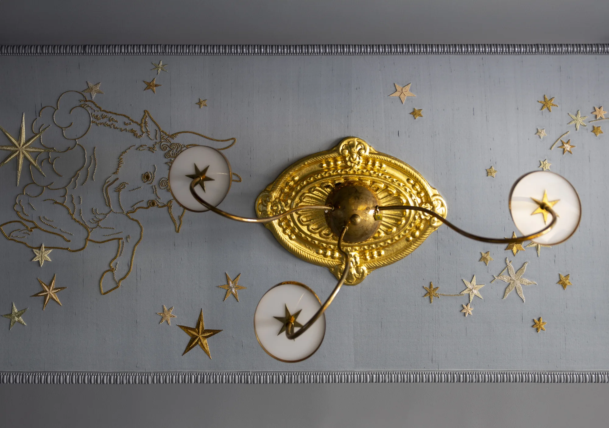 Gilt sconce among hand-applied gold stars on the de Gournay wallpaper