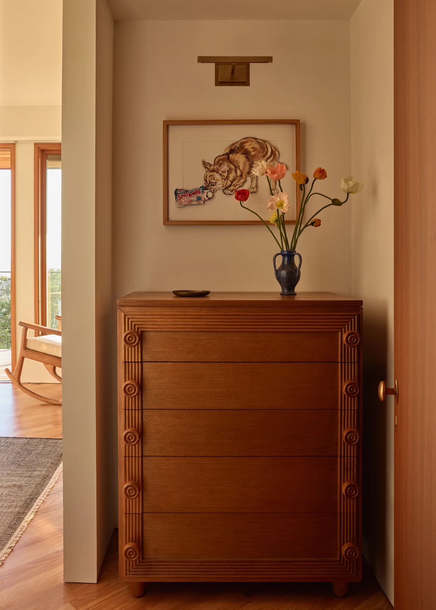 Wood dresser with cut flowers beneath a framed cat drawing
