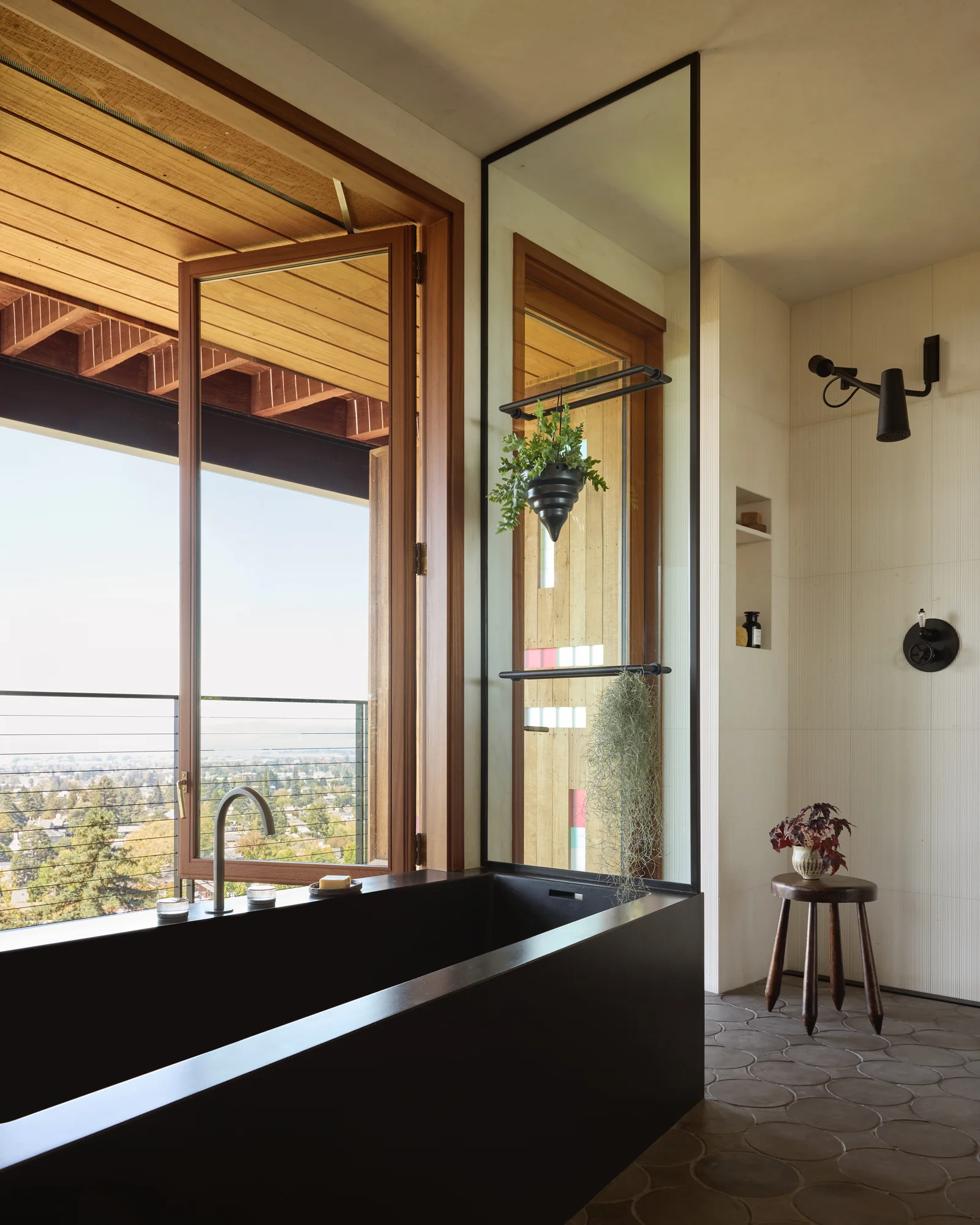 Black angled soaking tub set against floor-to-ceiling glass